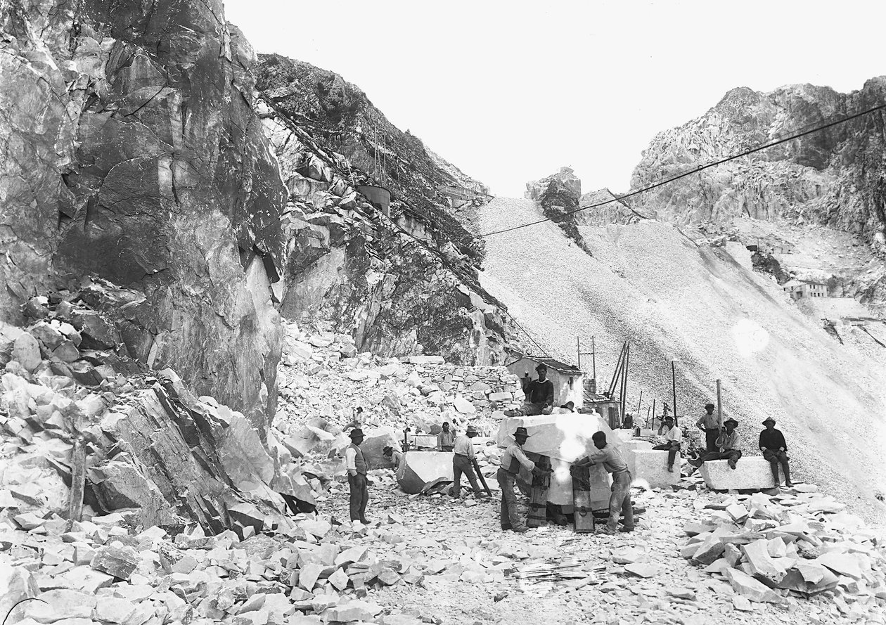 Excavators at work at a marble quarry in the Apuan Alps, Tuscany. Some of them are seated on blocks of marble already squared off. (b/w photo) by A. Corsini