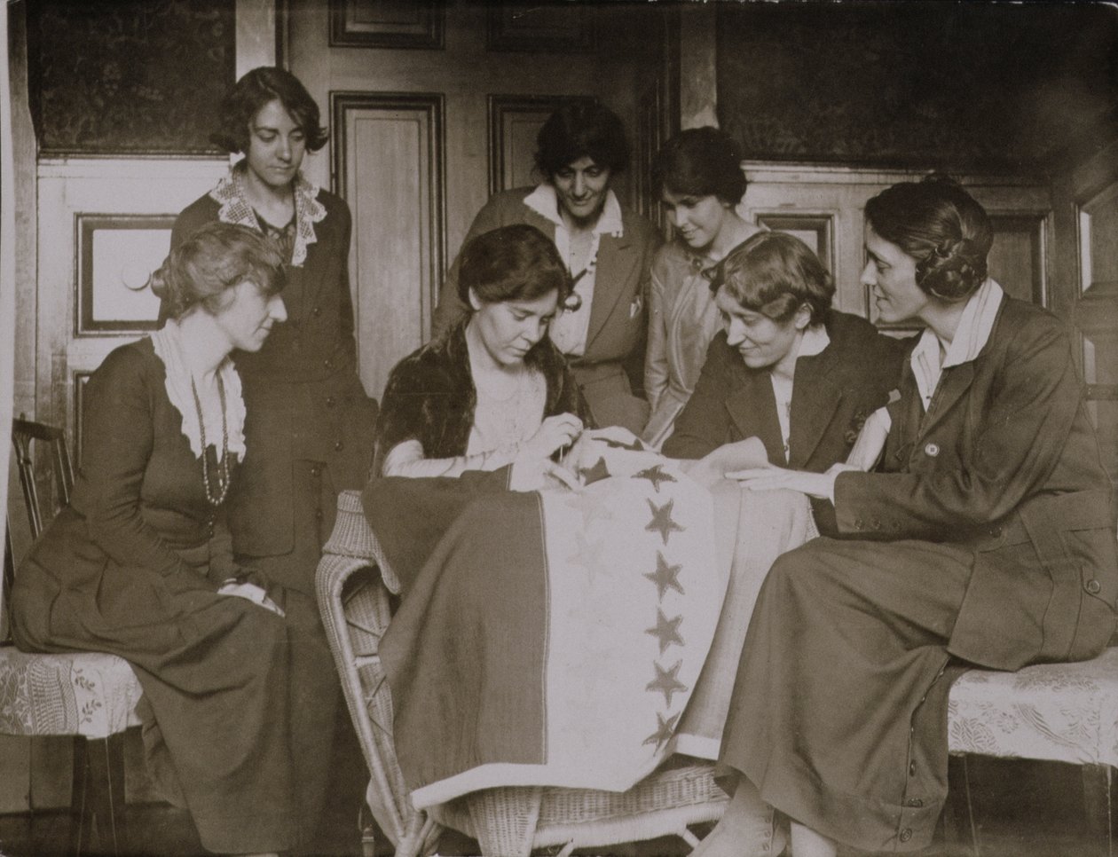 Alice Paul, diğer kadınların baktığı oy hakkı bayrağına yıldız dikiyor, 1920 dolayları by American Photographer