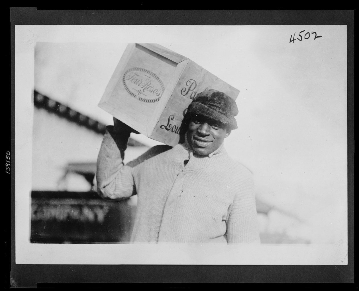 Omzunda bir kasa "Four Roses" viski taşıyan Afrikalı Amerikalı adam, muhtemelen ABD İç Gelir Bürosu tarafından el konuldu. by American Photographer