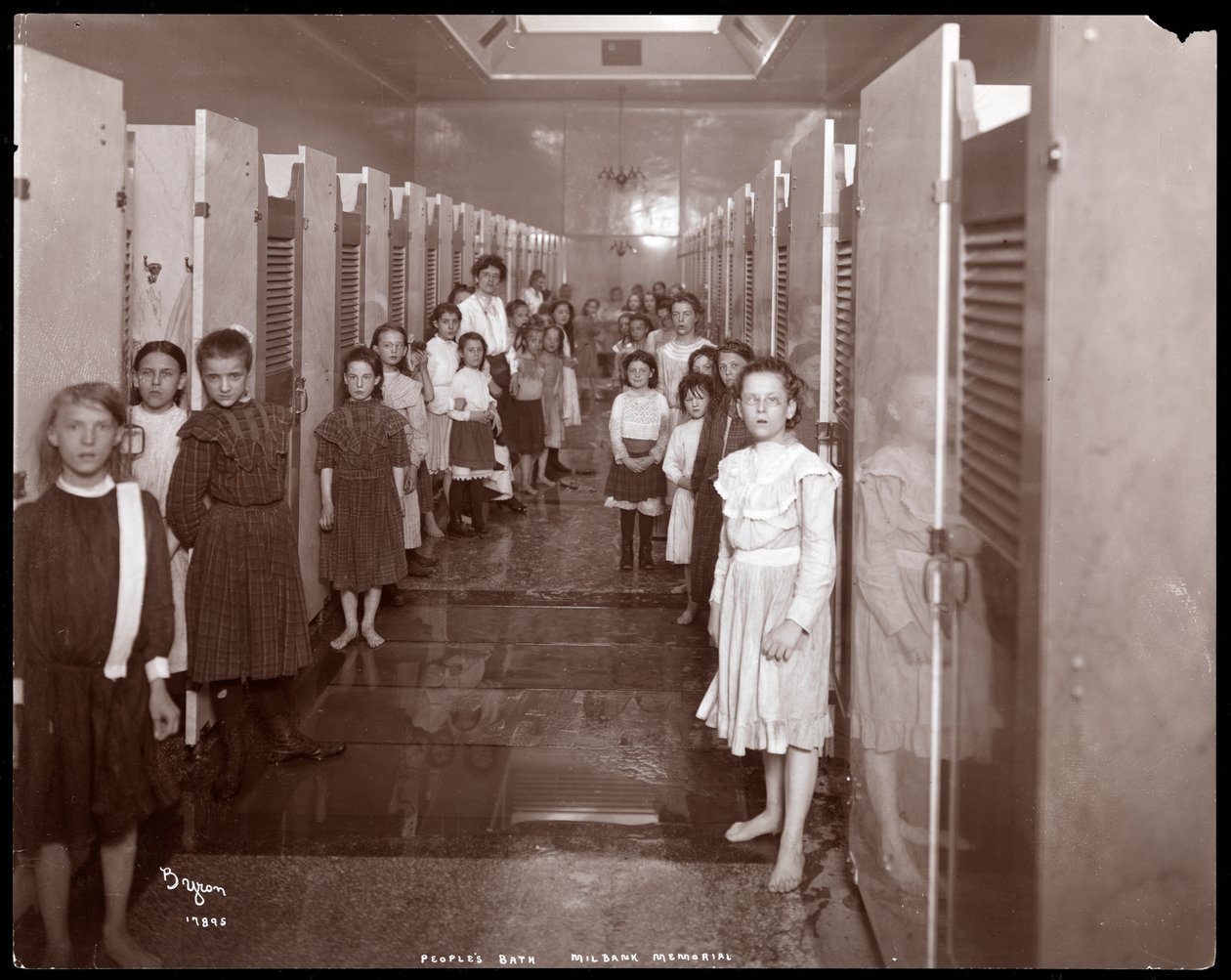 Interior view of young women standing in front of bathing stalls at the People