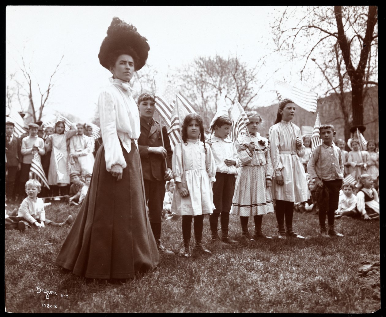 Woman with children holding flags on Arbor Day at Tompkins Square Park, New York, 1904 (silver gelatin print) by Byron Company