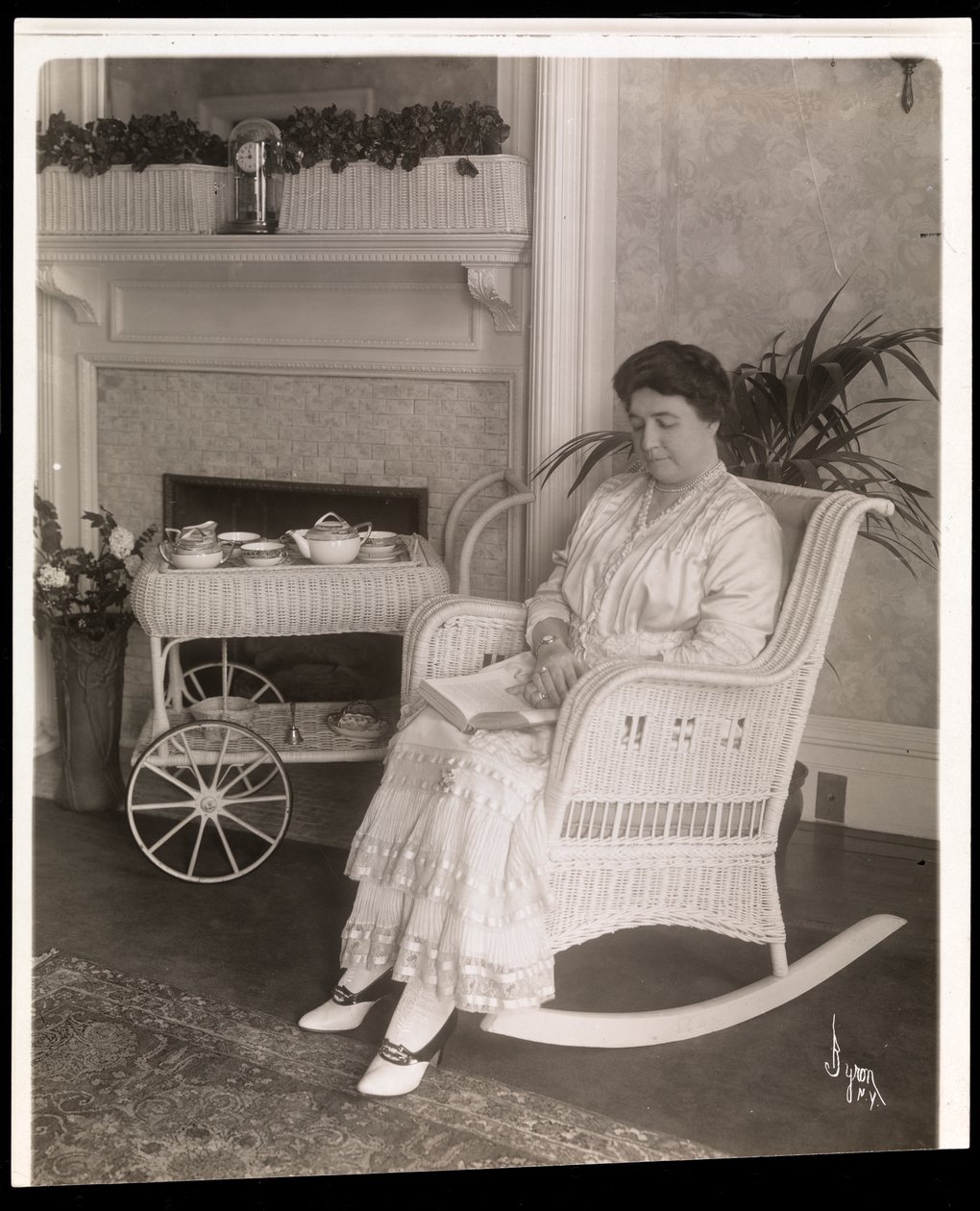 Bayan Howard, 200, 5th Avenue, New York, 1915-6 adresindeki evinde sallanan sandalyede bir kitapla oturuyor (gümüş jelatin baskı) by Byron Company