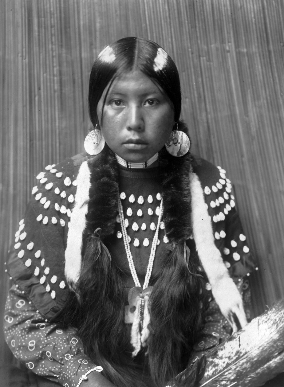 Kalispel Kızılderili kadın, saçına beyaz çizgiler boyanmış, kabuk disk küpeler, geyik dişleriyle süslenmiş battaniye elbisesi giymiş, c. 1910, fotoğraf Edward S. Curtis by Edward Sheriff Curtis