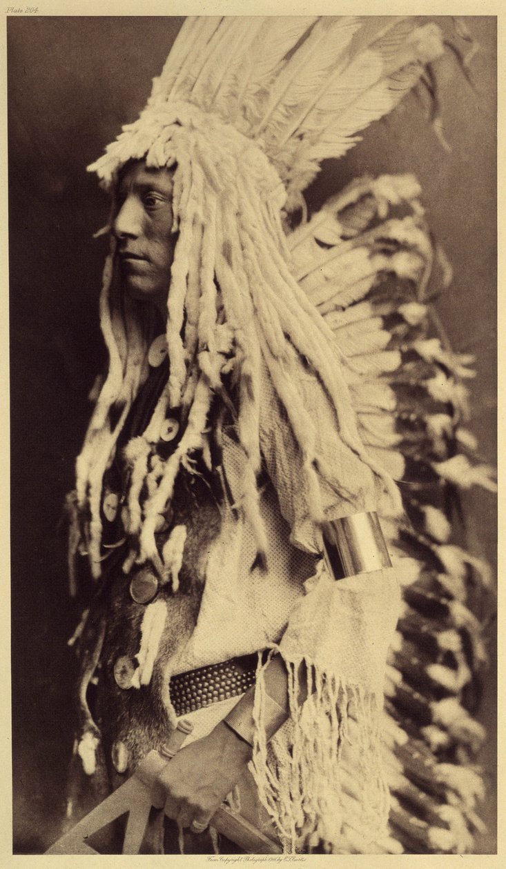 Yaşlı Kişi, Piegan. Genç erkekler, savaşçı babalarının kıyafetlerini giymek için halk şenliklerinin hiçbir fırsatını kaçırmazlar. Fotoğraf, Edward S. Curtis (1868-1952) tarafından Kuzey Amerika Kızılderilileri hakkında yayınlanan ansiklopedinin 6. cildinde by Edward Sheriff Curtis