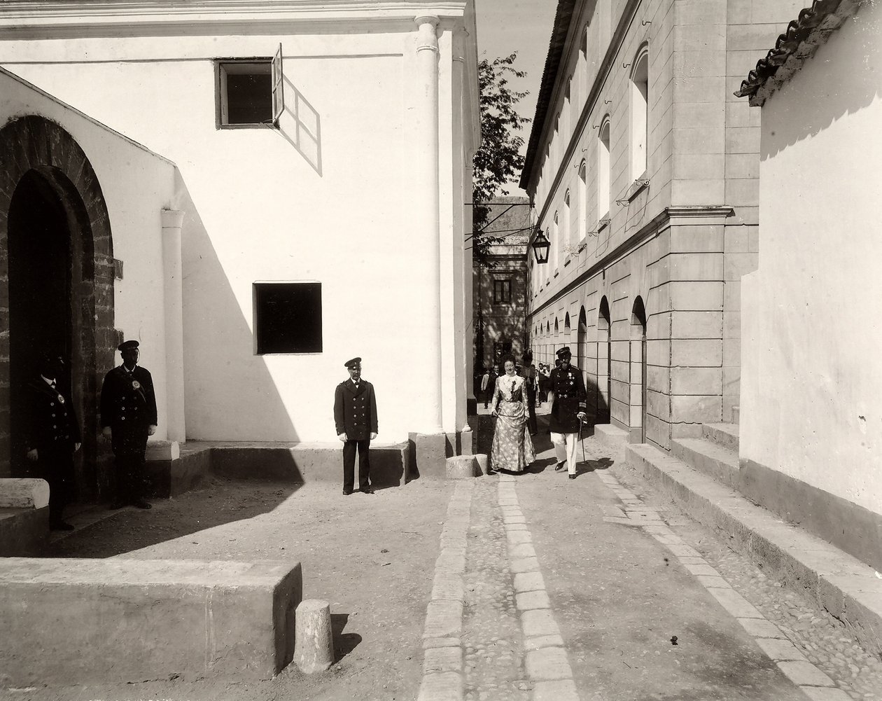 Üniformalı erkekler, zarif giyimli bir kadına eşlik eden Lo Zucco çiftliğinin kilisesine doğru eşlik ediyor, Sicilya, 1900 by Eugenio Interguglielmi