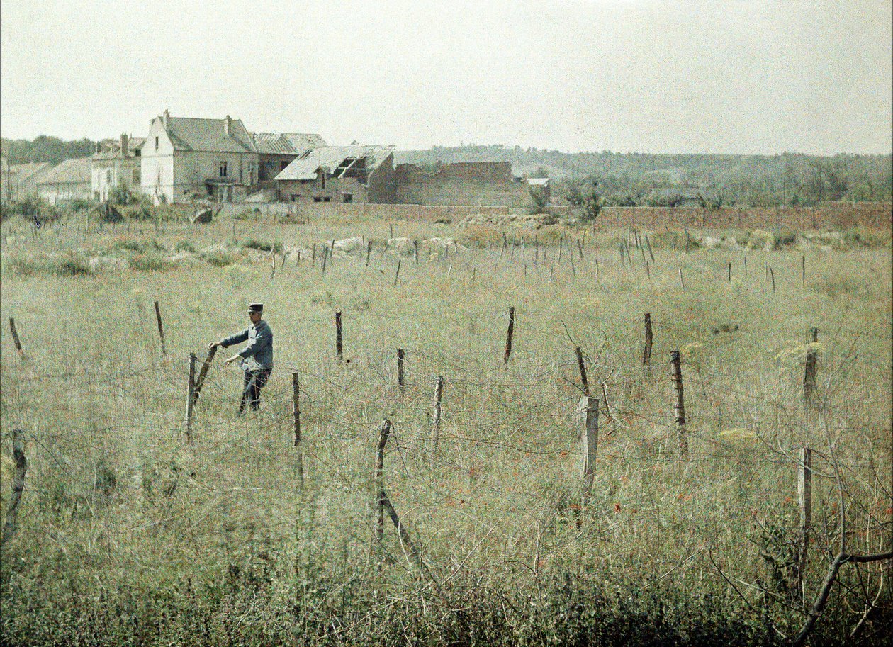 Bir Fransız subayı Fransız mevzilerinin etrafındaki dikenli telleri inceliyor, Soissons, Aisne, Fransa, 1917 (otokrom) by Fernand Cuville