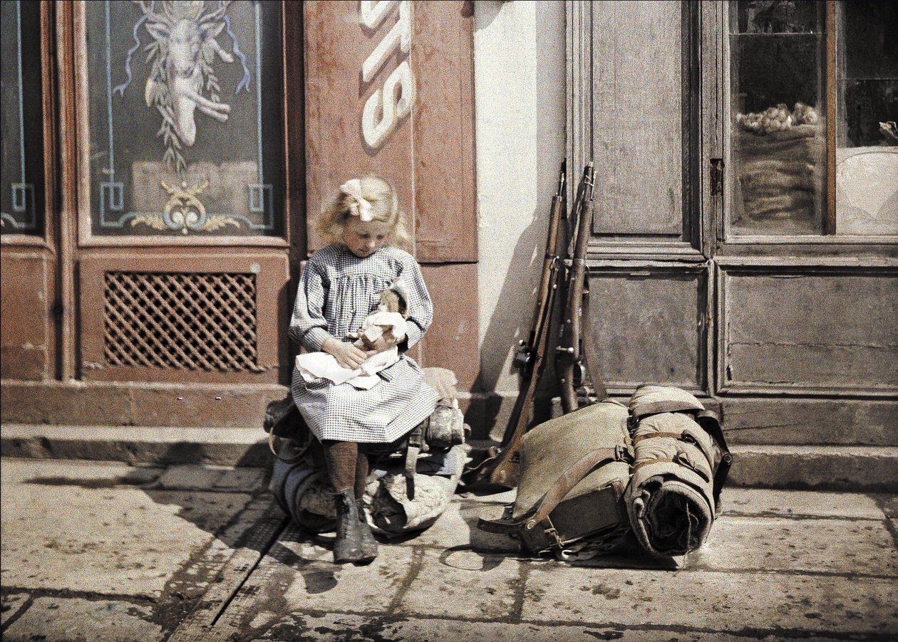 Oyuncak bebeğiyle oynayan küçük bir kız; iki silah ve bir sırt çantası yerde, Reims, Marne, Fransa, 1917 (otokrom) by Fernand Cuville