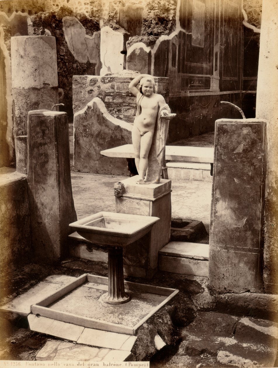 Çıplak genç bir çocuğun heykelinden oluşan bir çeşme. Çeşme, Pompei'deki Balcone Evi pensilesindedir. by Giorgio Sommer