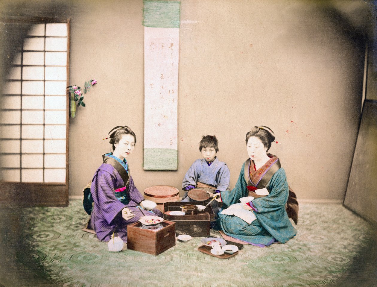 İki kadın ve bir çocuk, bir hasırın üzerinde oturup öğle yemeği yiyor, 1890 dolayları (el renkli fotoğraf) by Japanese Photographer