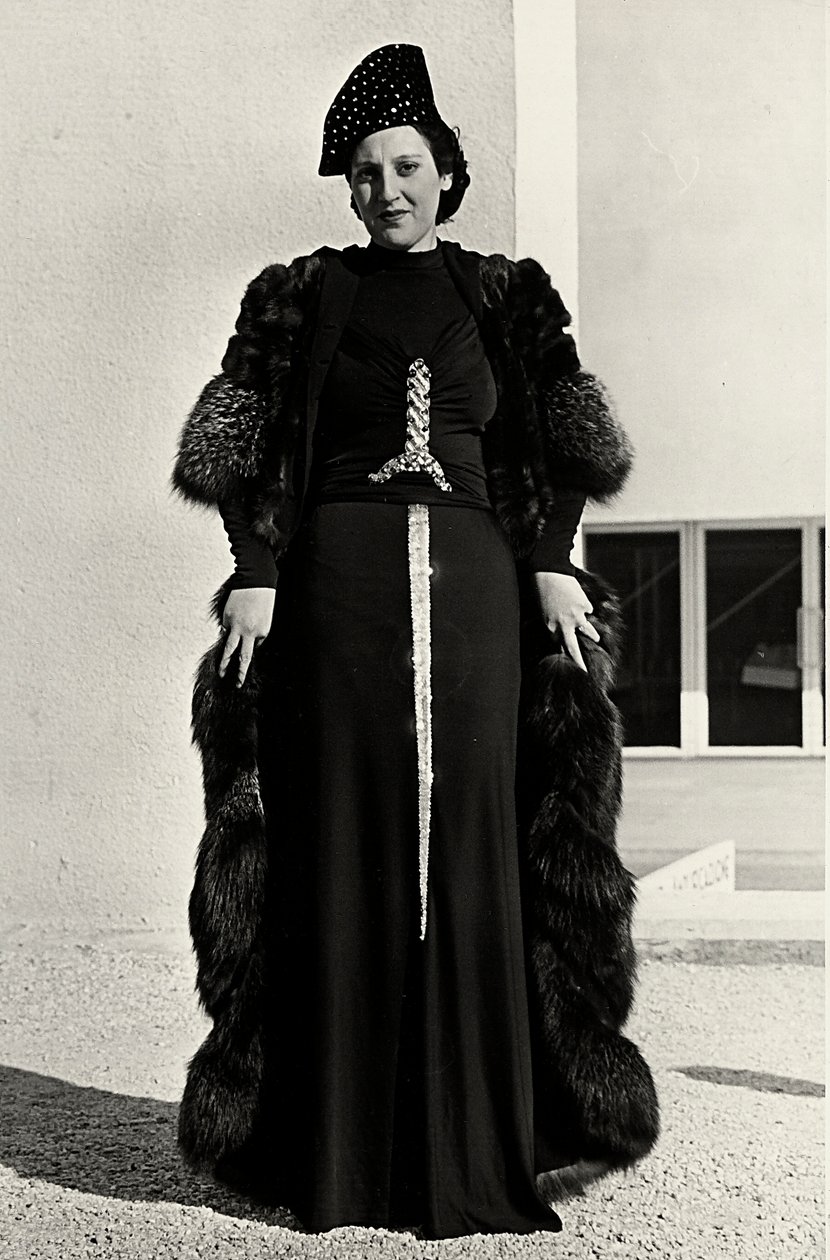 İtalyan moda evi "Dragoni" tarafından yaratılan gece elbisesi modeli. Yazının yazı tipi, kılıç şeklinde gösterişli payetli bir bezemeye sahiptir. Bir şapka ve kürk palto, topluluğu tamamlıyor. (s/b fotoğraf) by Luis Bogino