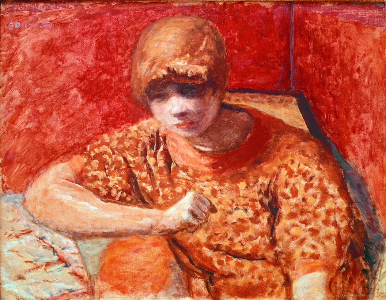 Turuncu bluz Oturan genç rüya gibi kadının kırmızı arka planda bir masası var. Pierre Bonnard