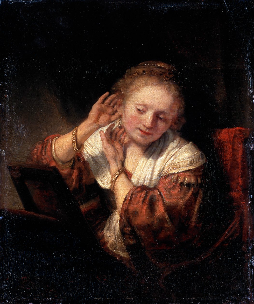 Küpe takmaya çalışan genç kadın, 1657. by Rembrandt van Rijn