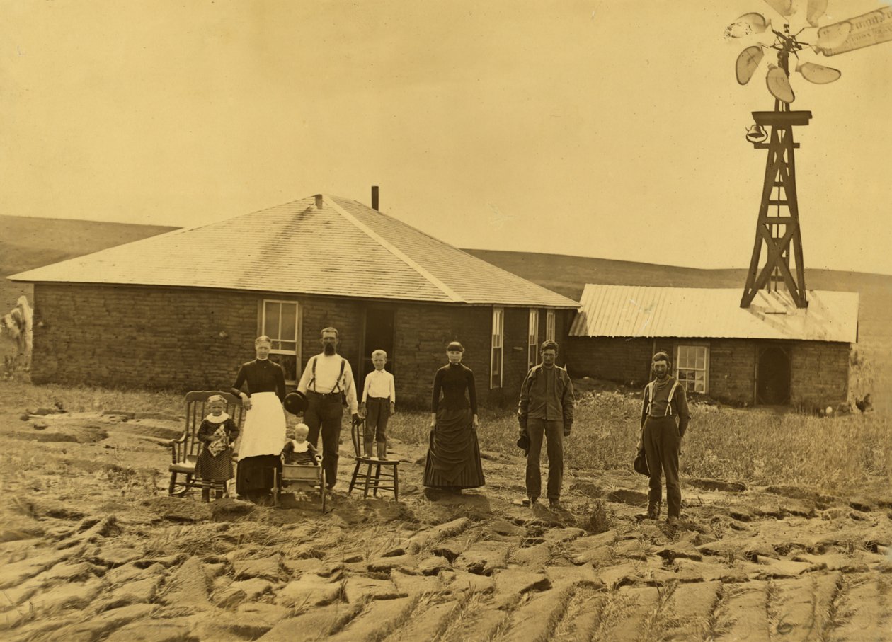 Nebraska, Custer County'deki bitişik binanın çatısında bir yel değirmeni olan çim evlerinin dışında çiftçi ailesi, 1885 dolayları (s/b fotoğraf) by Solomon D. Butcher