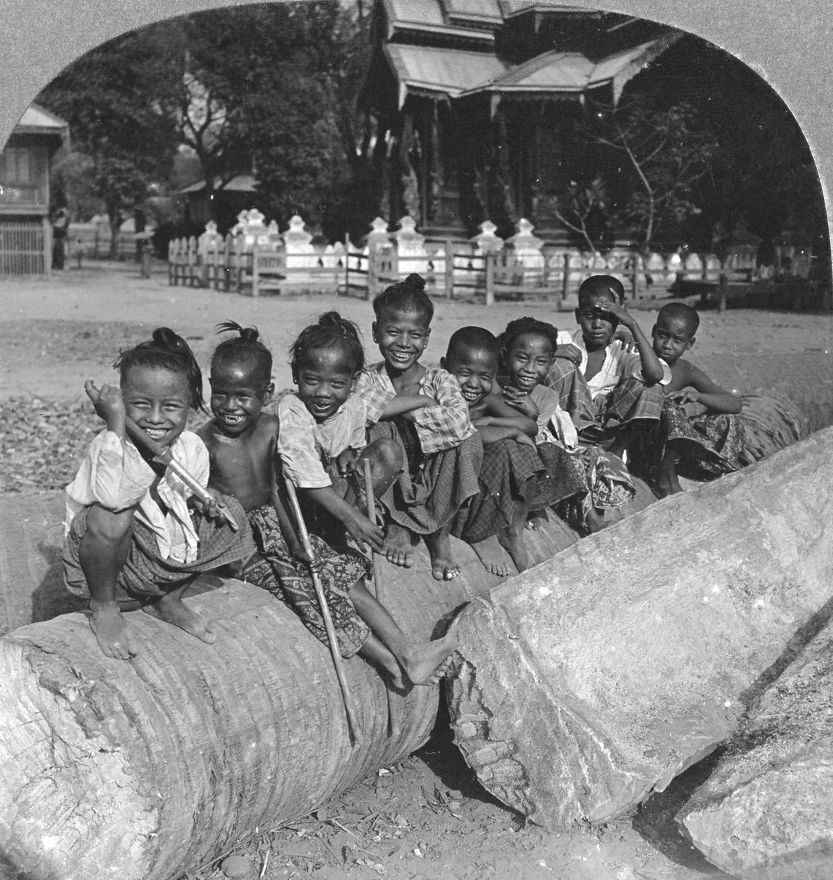 Bir palmiye kütüğünün üzerinde oturan Birmanyalı çocuklar, Burma, 1908 by Stereo Travel Co