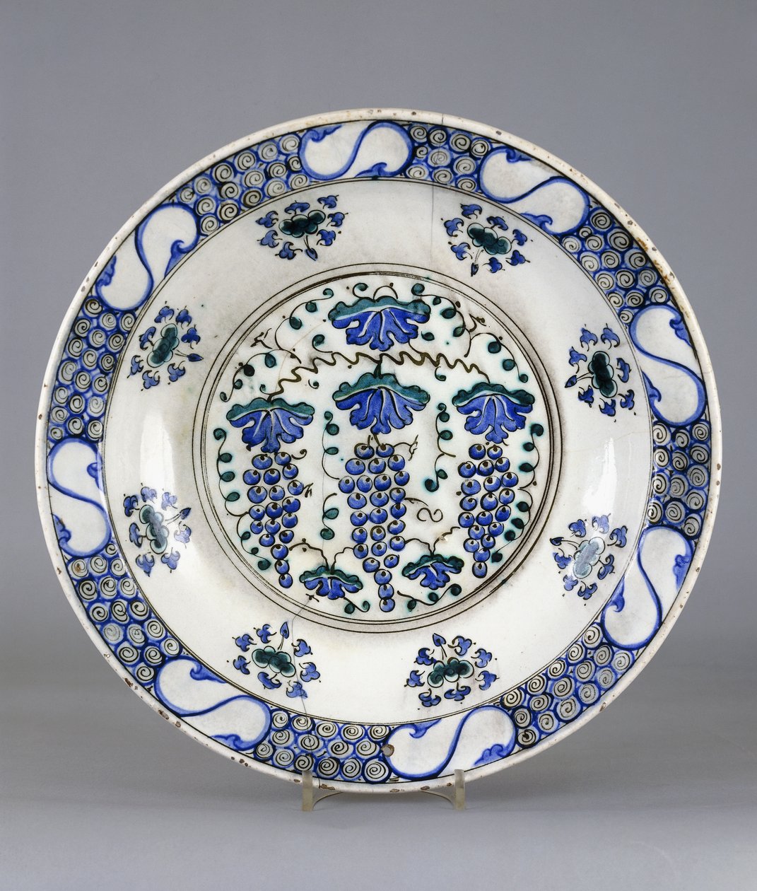 Ortasında üç salkım üzüm ve asma yaprağının betimlendiği yuvarlak bir İznik çanak çömlek, 1570 dolayları (seramik) by Turkish School