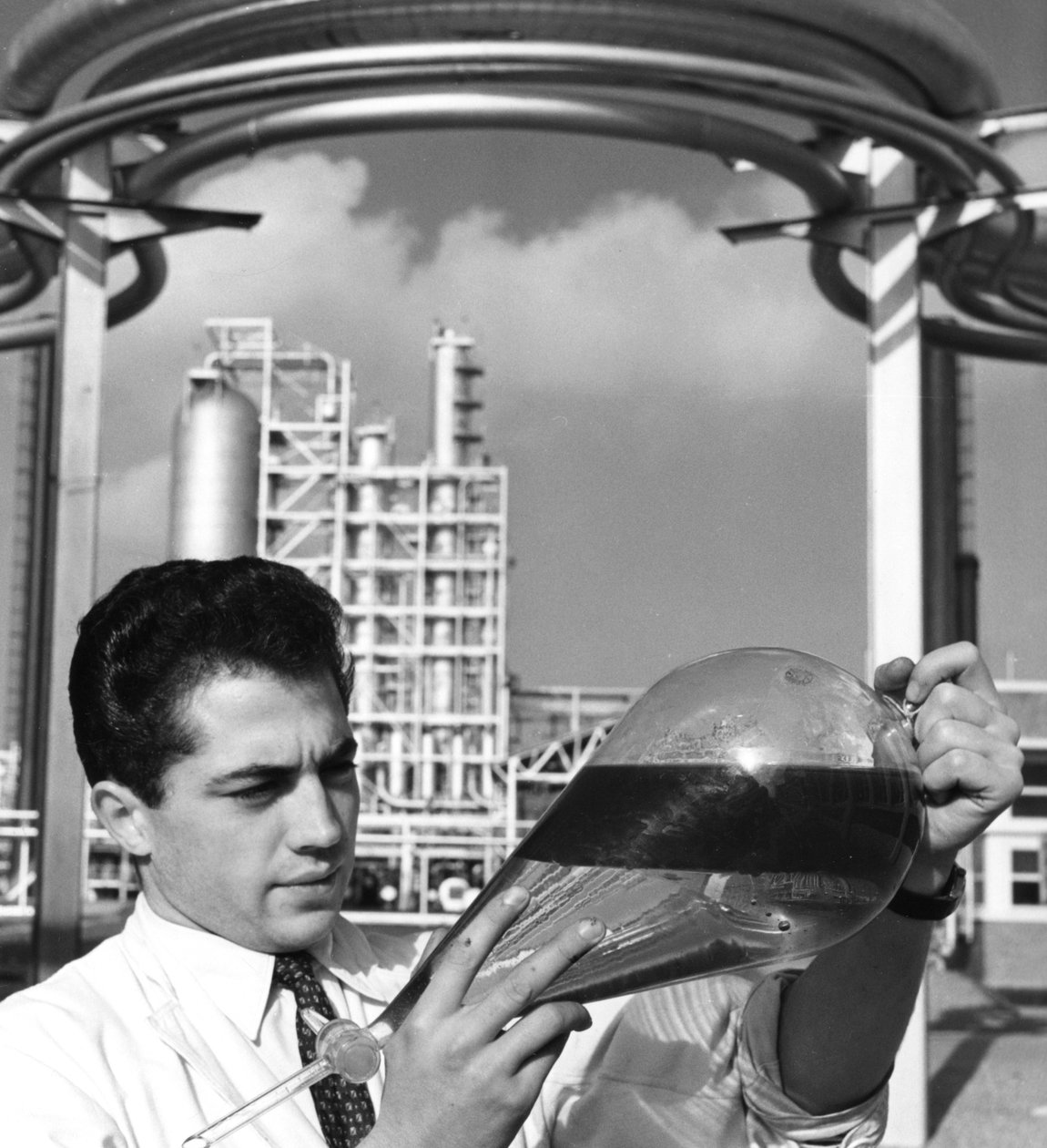 Bir laboratuvar çalışanı petrolün ayırıcı bir hunisini tutuyor, Dunkirk rafinerisi, Fransa, 1950