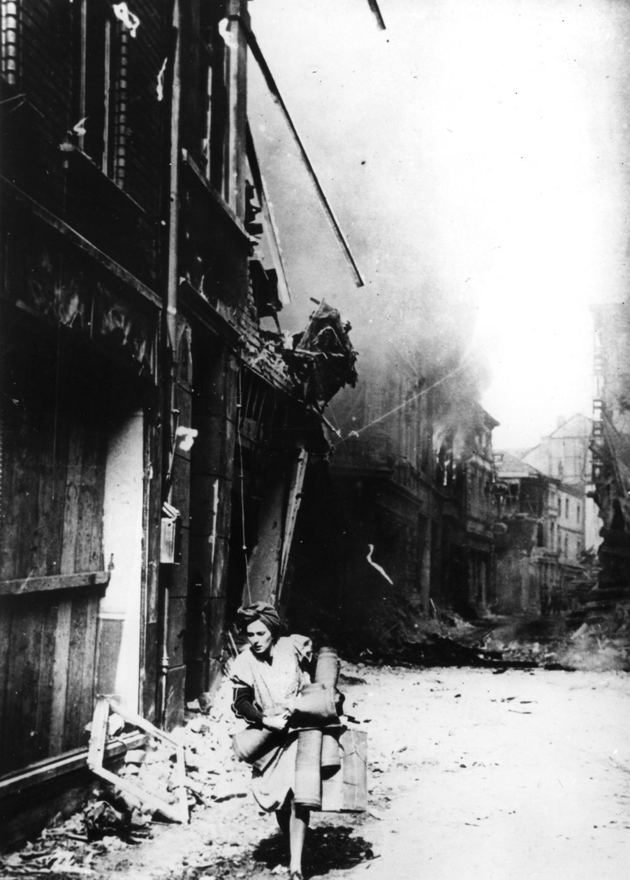 Bombalanmış bir sokakta yanan evinden çıkan bir kadın, Almanya, 1945 by Unbekannt