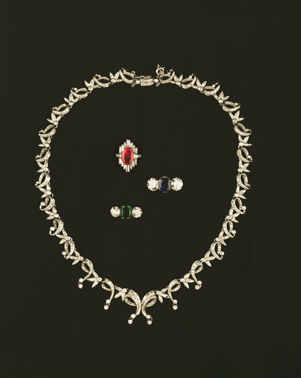 Art Deco kaydırma ve yaprak tasarım kolye; yakut ve pırlanta baget küme yüzük; safir ve pırlanta üç taşlı yüzük; zümrüt ve pırlanta üç taş yüzük by Unbekannt Unbekannt