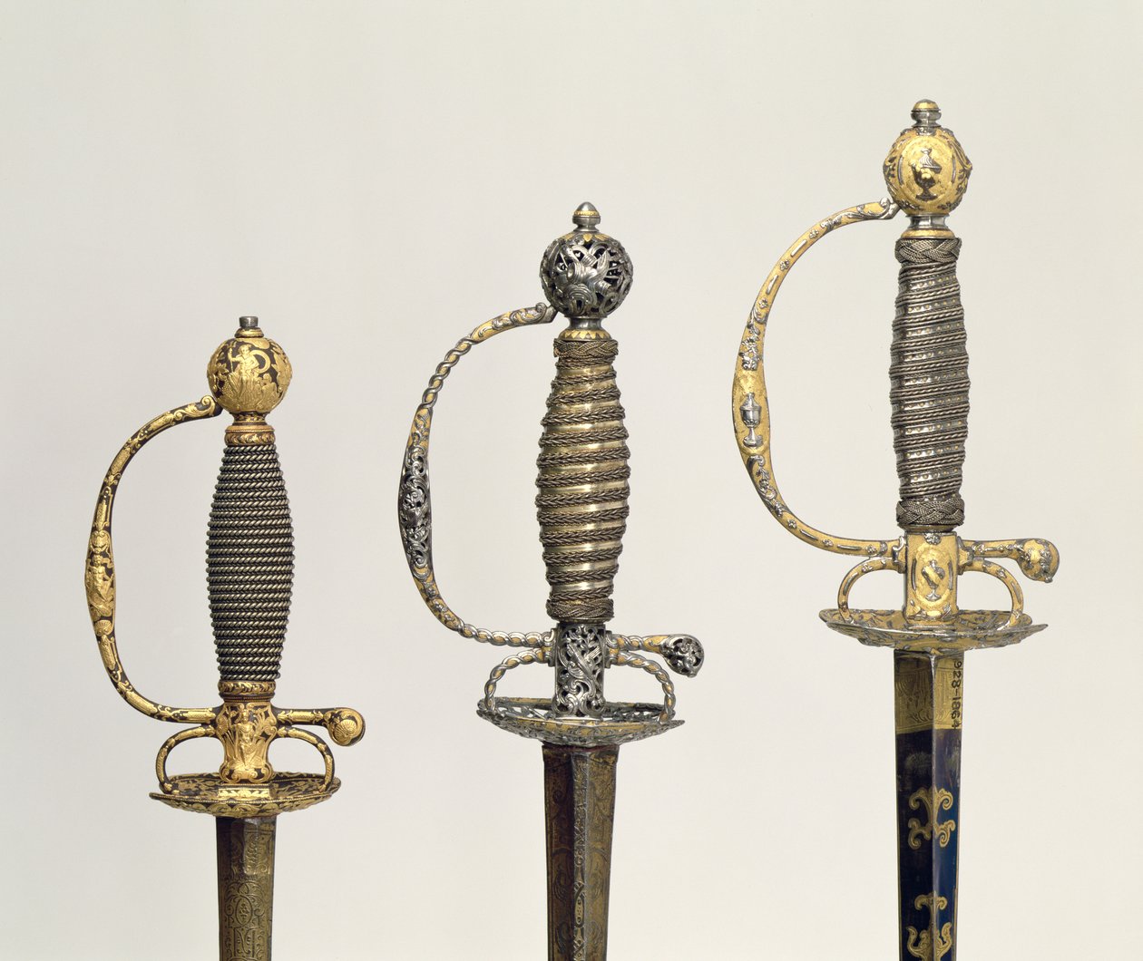 Üç Fransız kılıcının kabzaları: çelikten biri, maviye boyanmış ve altın desenlerle kaplanmış, c.1730; biri delinmiş ve yontulmuş çelikten ve matlaştırılmış altından taşlanmış, c.1760; yontulmuş çelikten biri, gr by Unbekannt Unbekannt