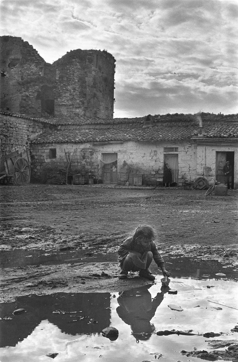 Çamurla çevrili bir su birikintisinde kağıt tekneyle oynayan genç kız, Venosa, Basilicata, İtalya by Unbekannt