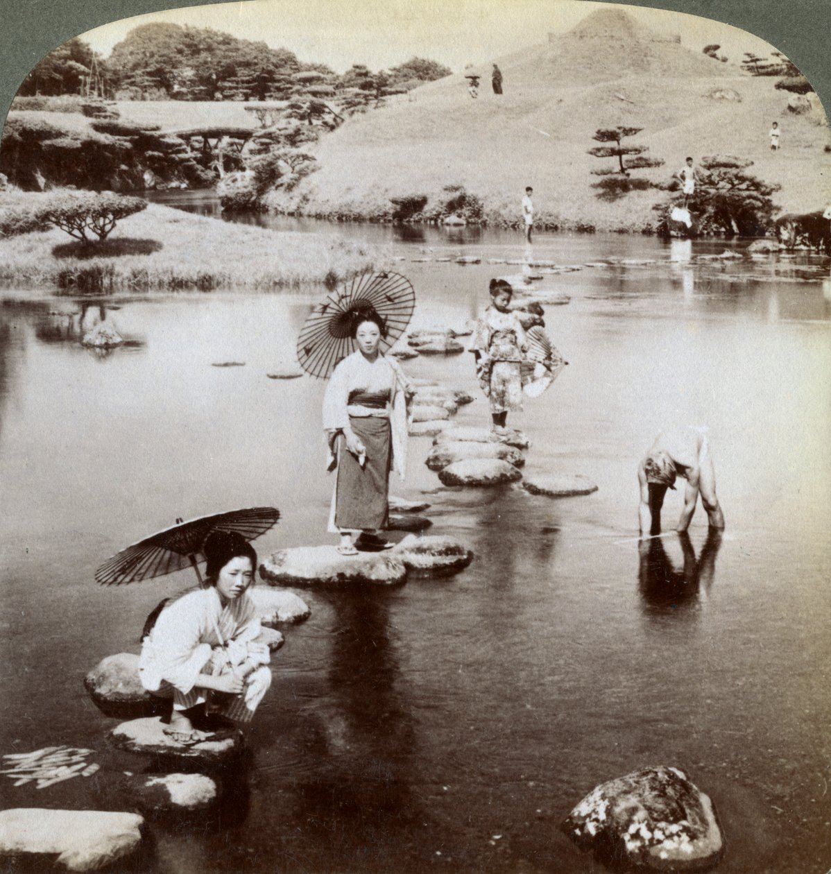 Basamak taşları üzerinde gölü geçen kadınlar, Suizen-ji Bahçesi, Kumamoto, Japonya, 1904. by Underwood and Underwood