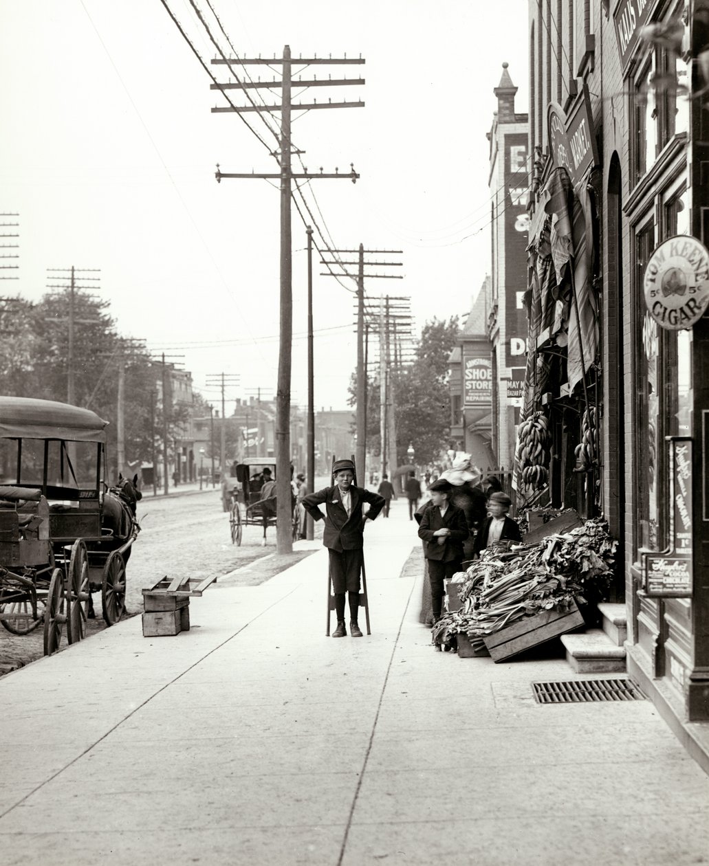 A boy with stilts standing in front of the F.J. Voepel Market at 4874 Easton Avenue, at the southeast corner of Easton and Euclid. Easton was later known as Dr. Martin Luther King Drive by Unknown