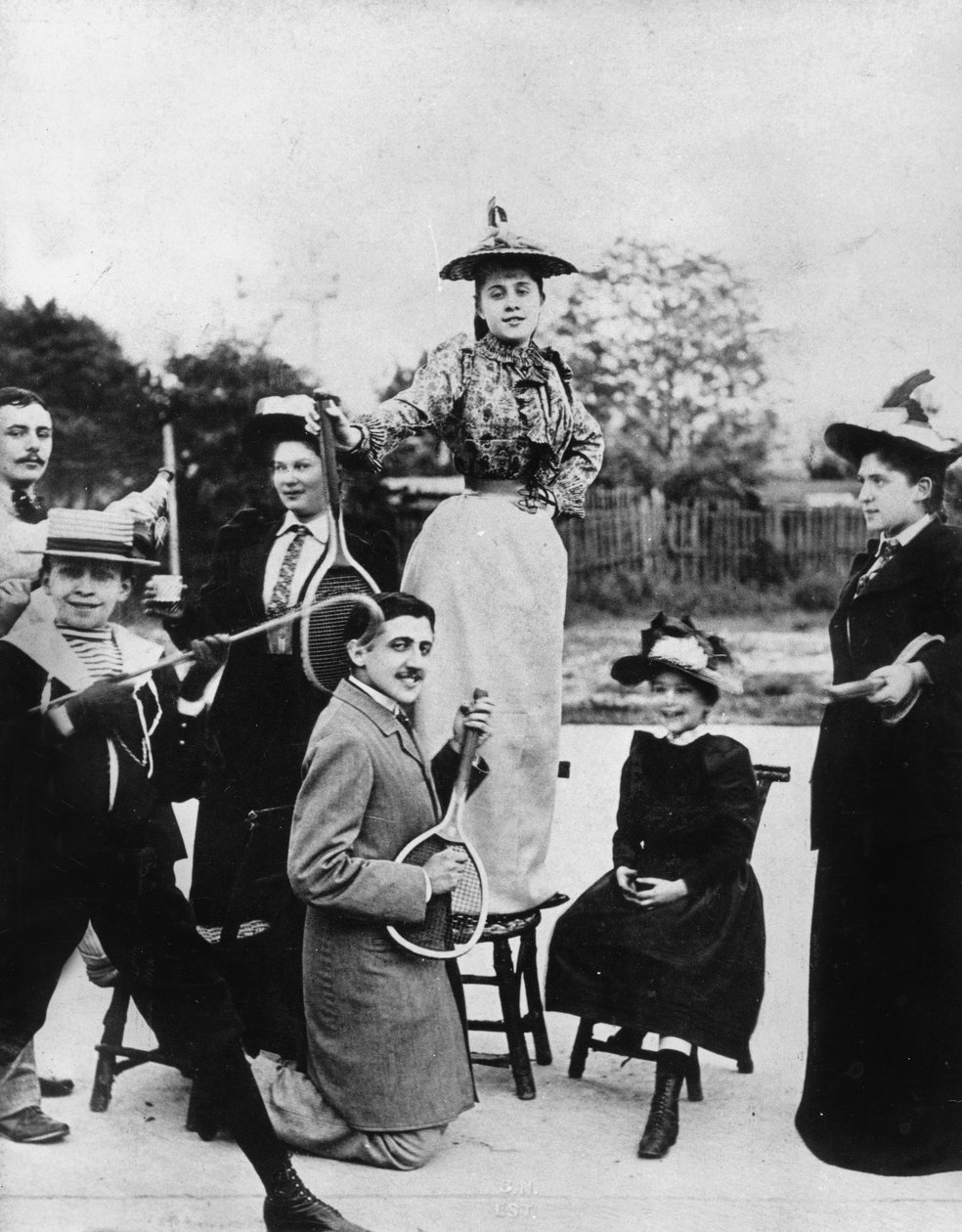 Marcel Proust (1871-1922), Neuilly'de (Fransa) bir sandalyede duran Jeanne Ponquet'nin önünde bir tenis raketi ile diz çökmüş, 1892 by Unknown photographer