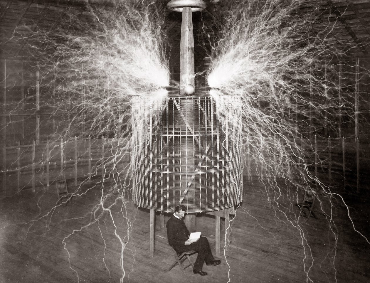 Nikola Tesla, Colorado Springs laboratuvarında “Büyüteç Vericisi” ile oturuyor by Unknown photographer