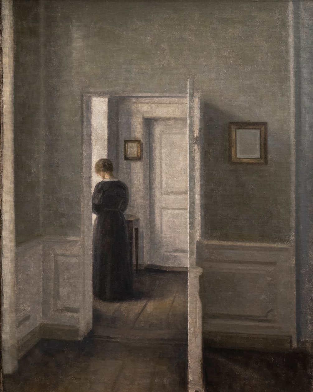 Ayakta duran bir kadınla iç mekan (tuval üzerine yağlı boya) by Vilhelm Hammershoi