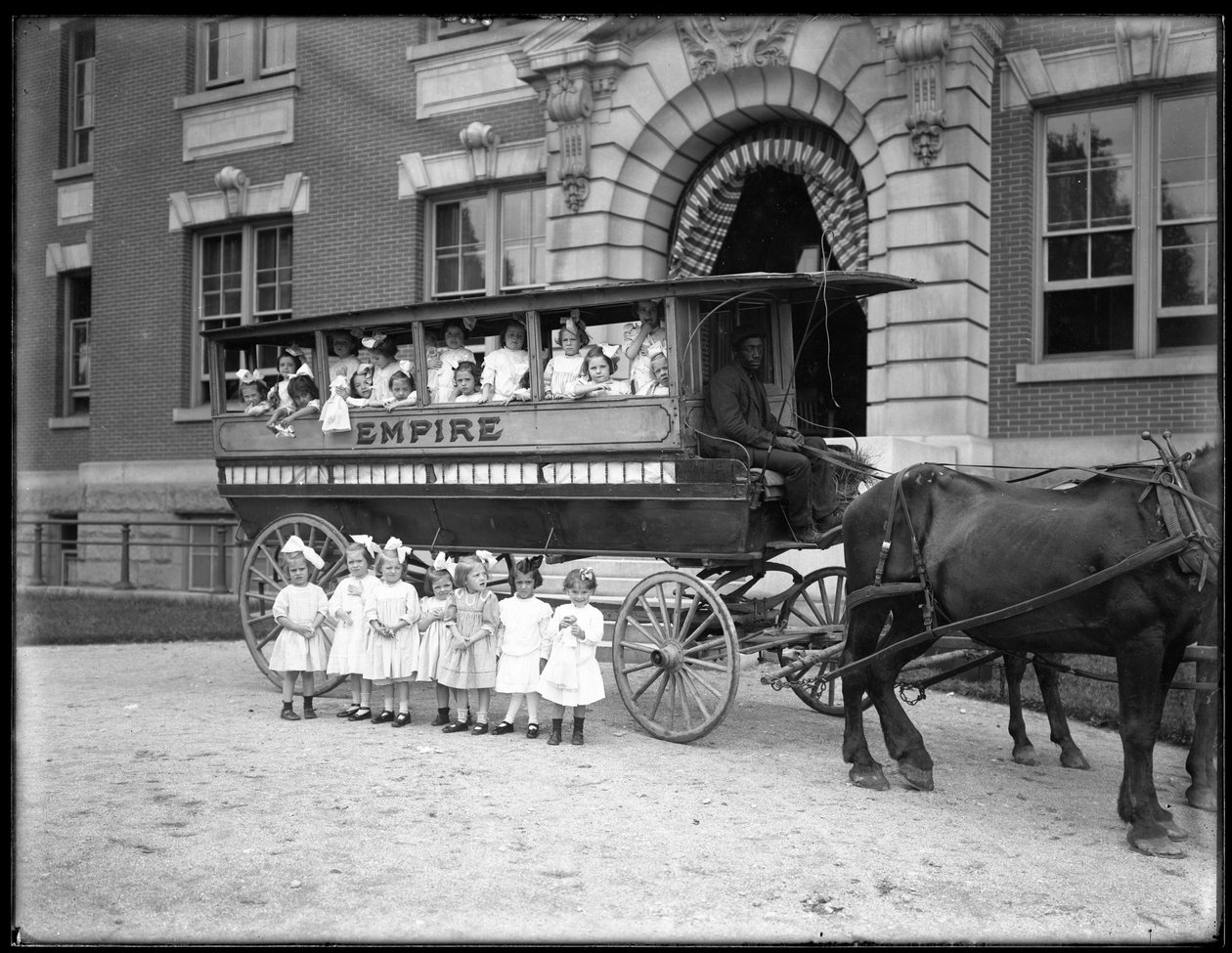 Küçük kızlar atlı bir vagonun içinde ve önünde, kimliği belirsiz bir binanın önünde poz veriyor, muhtemelen Roma Katolik Yetimhanesi, Kingsbridge, Bronx, 1910 dolayları by William Davis Hassler