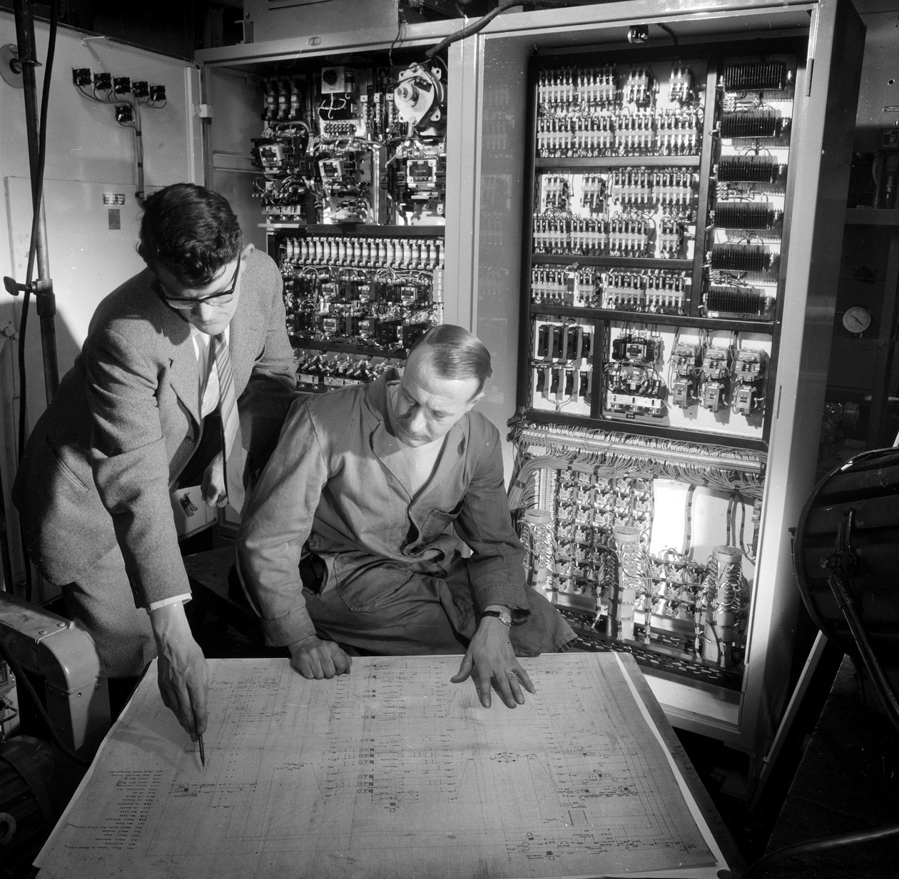 Mühendisler, inşa ettikleri elektronik kontrol panelinin önünde planları tartışıyorlar by Frederick (attr. to) Barnard