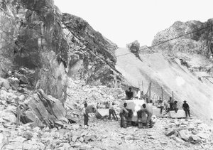 Excavators at work at a marble quarry in the Apuan Alps, Tuscany. Some of them are seated on blocks of marble already squared off. (b/w photo)