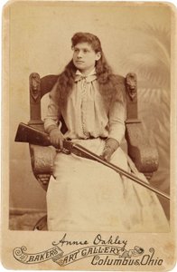 Annie Oakley: Annie Oakley:. Burada Efsanevi Keskin Nişancı, Kucağında Bir Pompalı Tüfekle Rönesans Tarzı Devasa Bir Sandalyede Oldukça Ağırbaşlı Oturuyor. Narin Kadınsı Özellikleri ve Dalgalanan Saçları, Doğadaki Engebeli Ortamını Gizliyor Görüntü ©Buyenl by American Photographer