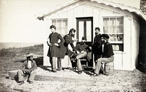 Beş İç Savaş askeri evinin dışındaki toprak verandada toplandı, Afrikalı Amerikalı genç yanlarında oturuyor, 1861-65 by American Photographer