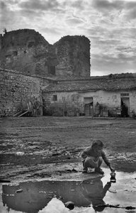 Çamurla çevrili bir su birikintisinde kağıttan kayıkla oynayan genç kız, Venosa, Basilicata, İtalya