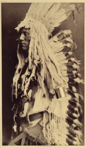 Yaşlı Kişi, Piegan. Genç erkekler, savaşçı babalarının kıyafetlerini giymek için halk şenliklerinin hiçbir fırsatını kaçırmazlar. Fotoğraf, Edward S. Curtis (1868-1952) tarafından Kuzey Amerika Kızılderilileri hakkında yayınlanan ansiklopedinin 6. cildinde by Edward Sheriff Curtis