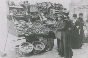 Bir bakkal, bir kadına hizmet ederken tezgahının yanında duruyor. by English Photographer