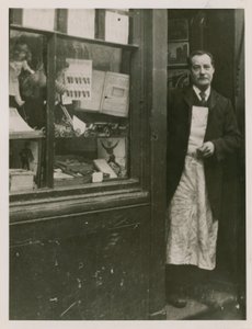 Dükkanının kapısında duran bir dükkan sahibi by English Photographer