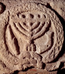 Yahudilik: yedi dallı (Menora veya Menora), palmiye ve trompetli bir şamdanla süslenmiş bir sinagogun bazaltındaki mimari unsur. Transjordan