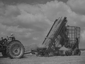 Mobil kasayı çeken traktör ve kasaya yüklenen saman by Joseph Hardman