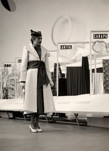 Couture evi "Lamma" tarafından oluşturulan bir paltoda model. Ürün, geniş bir kuşakla belden toplanmış ve yumuşak bir şapka ile tamamlanmıştır. Fotoğraf, kumaş sergisi için kullanılan bir salonda çekildi. (s/b fotoğraf) by Luis Bogino