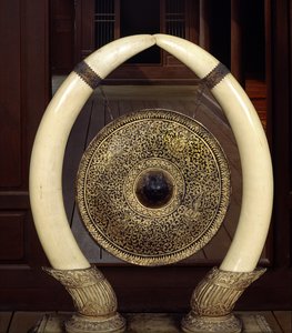 Fil dişlerinden sarkan bir gong (metal ve fildişi)