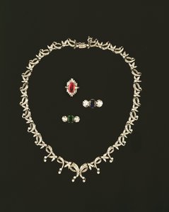 Art Deco kaydırma ve yaprak tasarım kolye; yakut ve pırlanta baget küme yüzük; safir ve pırlanta üç taşlı yüzük; zümrüt ve pırlanta üç taş yüzük