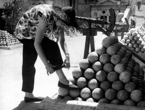 Bir kadın, Roma#39;daki Castel Sant#39;Angelo arazisindeki gülle yığınının üzerine ayağını koyarken pantolonunun manşetini düzeltiyor. by Unknown photographer