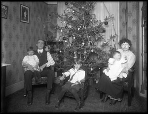 Bir Noel ağacının önünde oturan dairelerinde kimliği belirsiz bir ailenin resmi olmayan grup portresi, New York City, c.1915-16 by William Davis Hassler