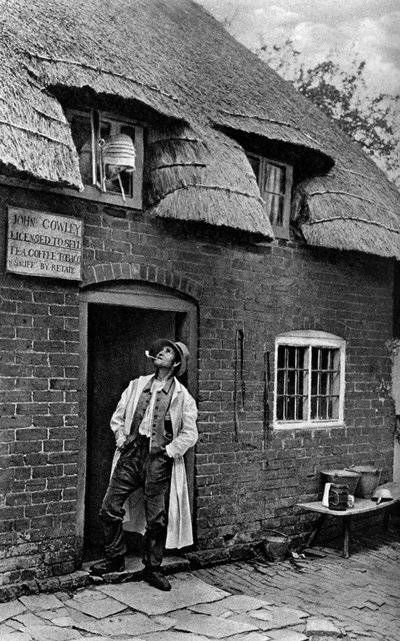 Bir dükkanın önünde pipo içen bir adam, Worcestershire, c1922. by A. W. Cutler