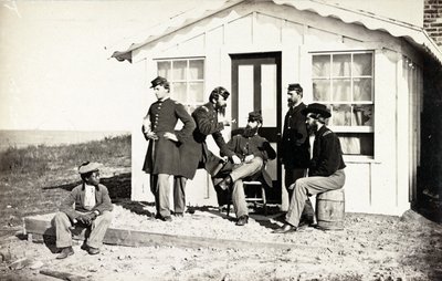 Beş İç Savaş askeri evinin dışındaki toprak verandada toplandı, Afrikalı Amerikalı genç yanlarında oturuyor, 1861-65 by American Photographer