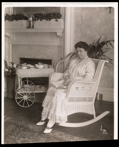 Bayan Howard, 200, 5th Avenue, New York, 1915-6 adresindeki evinde sallanan sandalyede bir kitapla oturuyor (gümüş jelatin baskı) by Byron Company