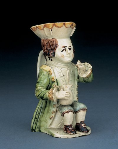 Toper toby sürahisi, kenarları kahverengi ve sarı dalgalı şapkası, sıraya kazınmış kahverengi saçları ve dizinde korkuluklu bir sürahi ile oturan beyaz bir rozet, c.1770 by English School