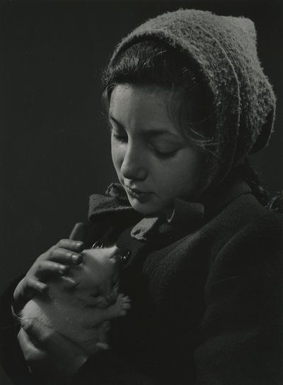 Kucağında beyaz bir kedi yavrusu tutan kız. 1950